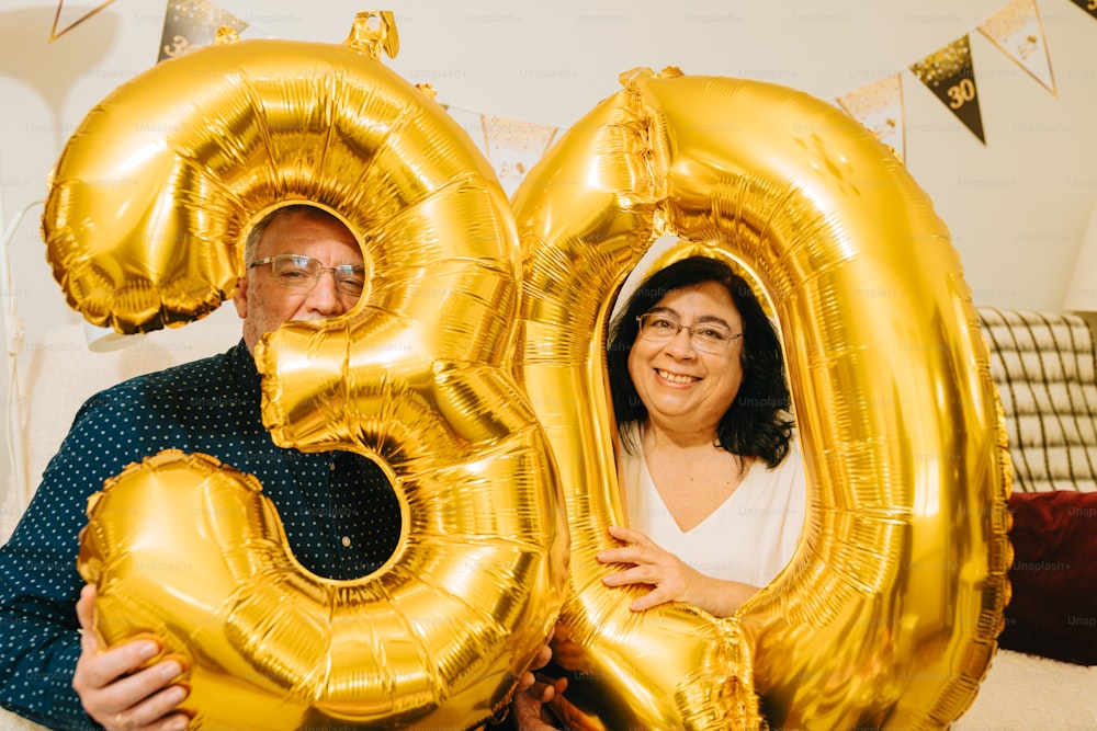 un uomo e una donna che reggono grandi palloncini dorati