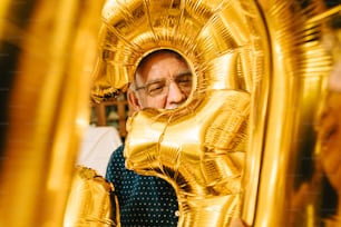 a man in a blue shirt and gold foil balloons