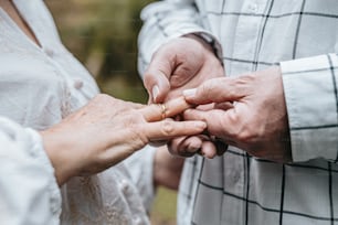 Un primer plano de una persona colocando un anillo de bodas en el dedo de otra persona
