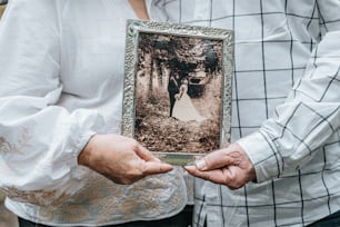 a man holding a picture of a woman in a wedding dress