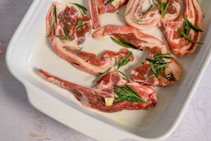 a tray of raw meat with herbs on top of it
