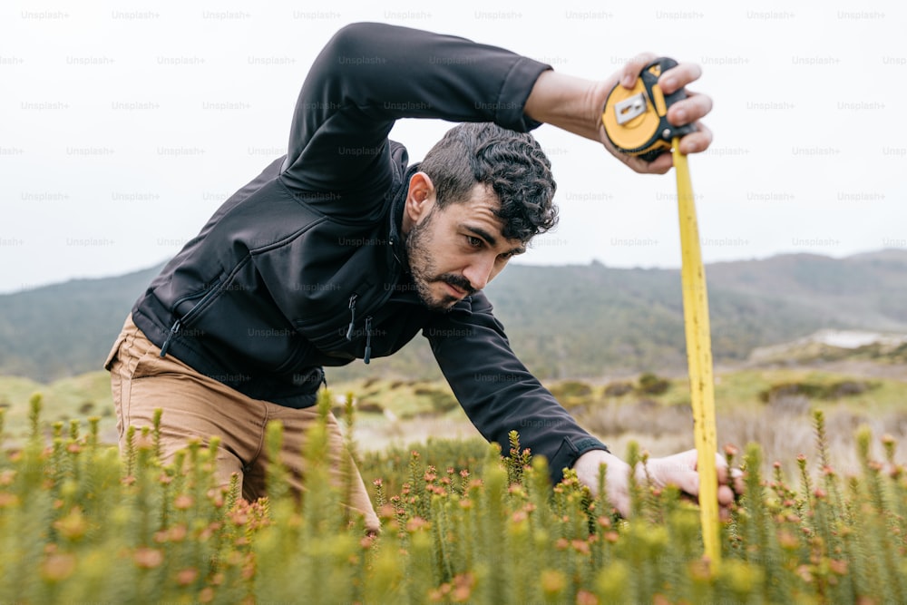 a man in a field with a measuring tape