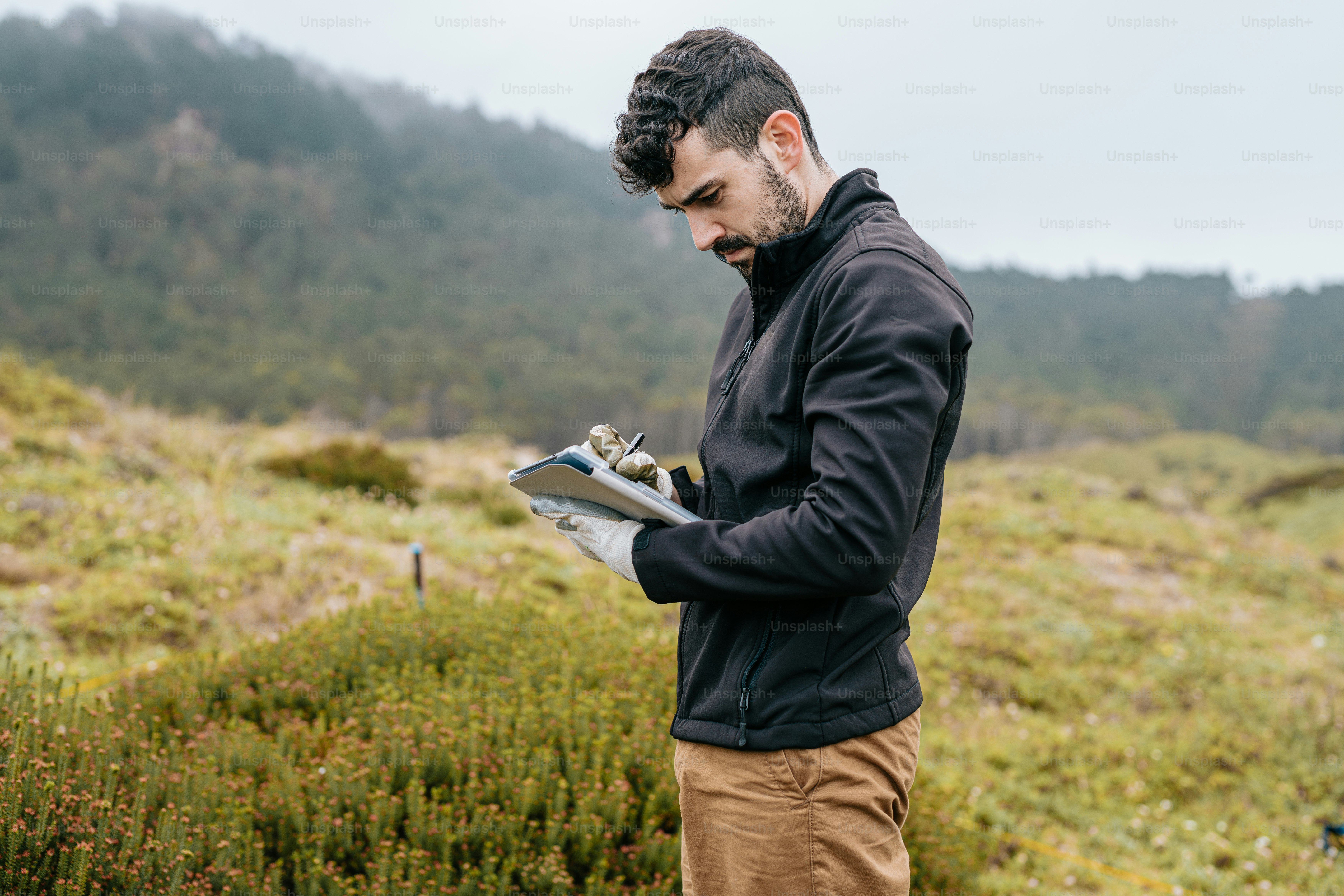 a man standing in a field looking at a piece of paper