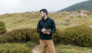 a man standing in a field holding a book