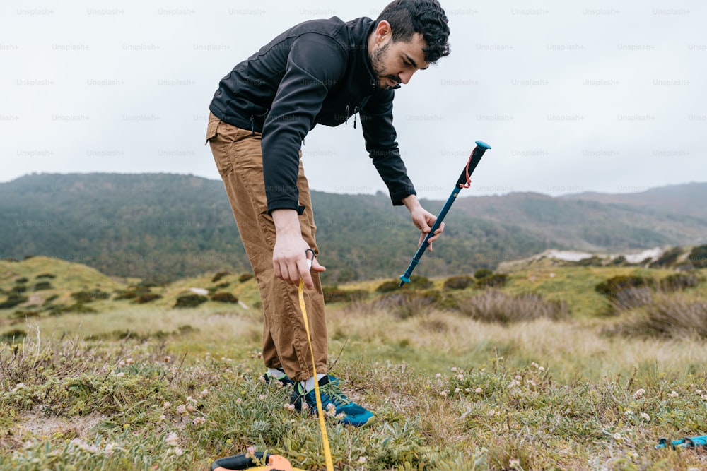 a man in a field with a pair of hiking poles