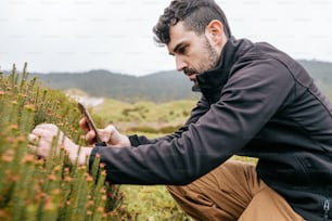 a man kneeling down looking at a cell phone