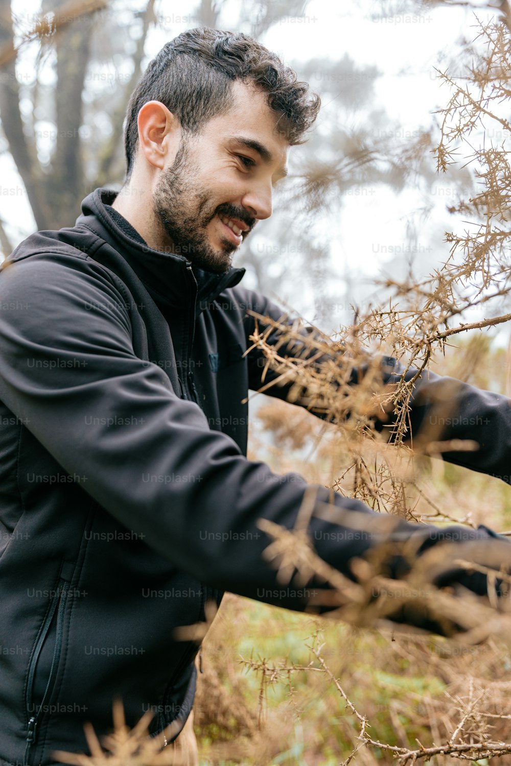 a man in a black jacket is holding a branch