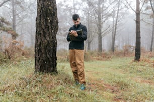 Un hombre de pie junto a un árbol en un bosque
