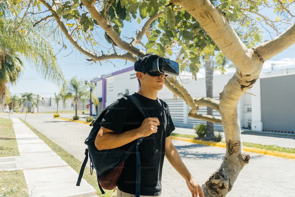 a man wearing a virtual reality headset standing next to a tree