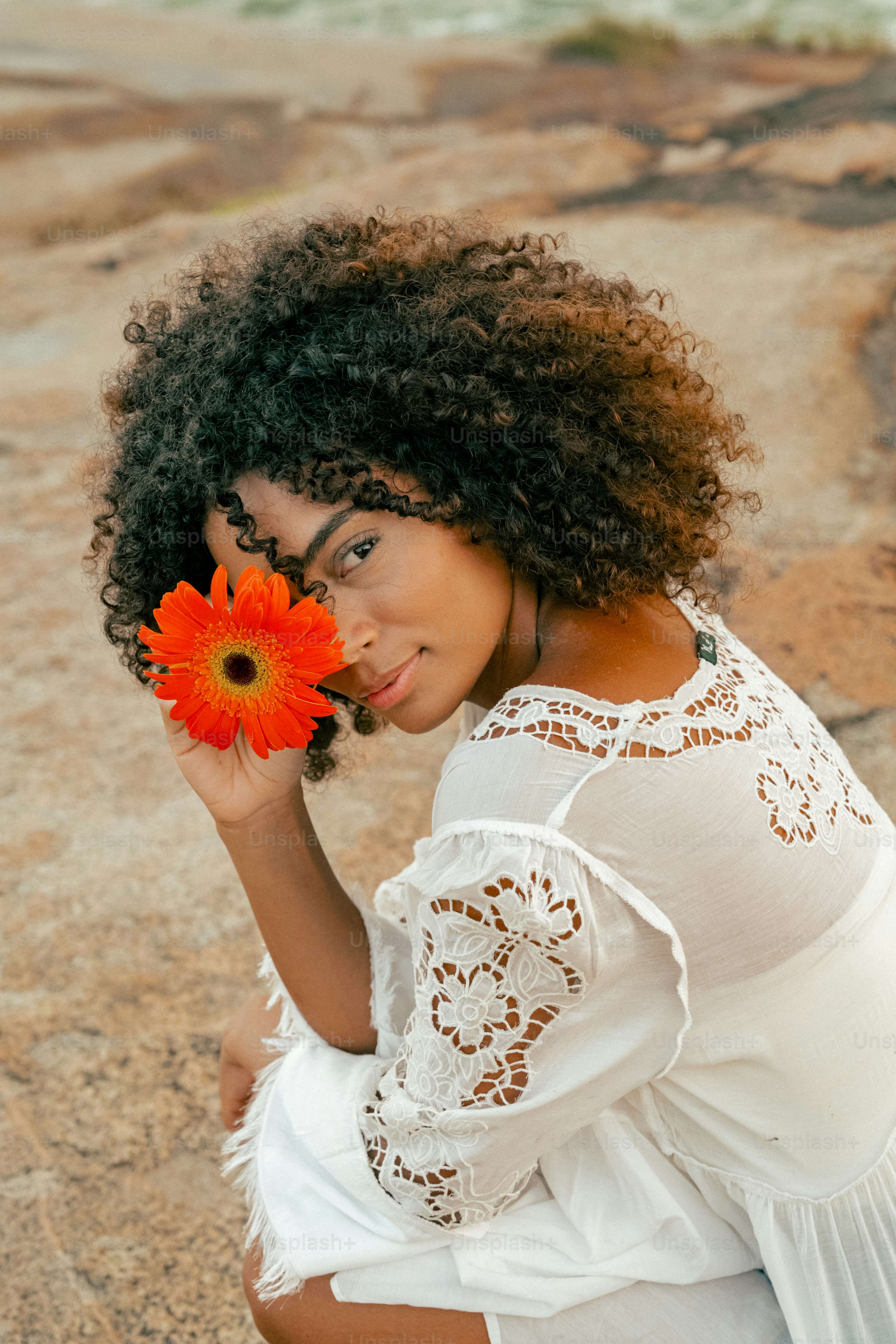 a woman sitting on a rock holding a flower