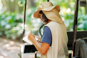 a man in a hat writing on a notebook