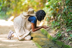 a person kneeling on the ground near a stream of water
