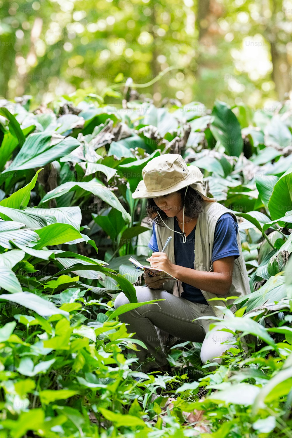 a woman kneeling down in a field of plants