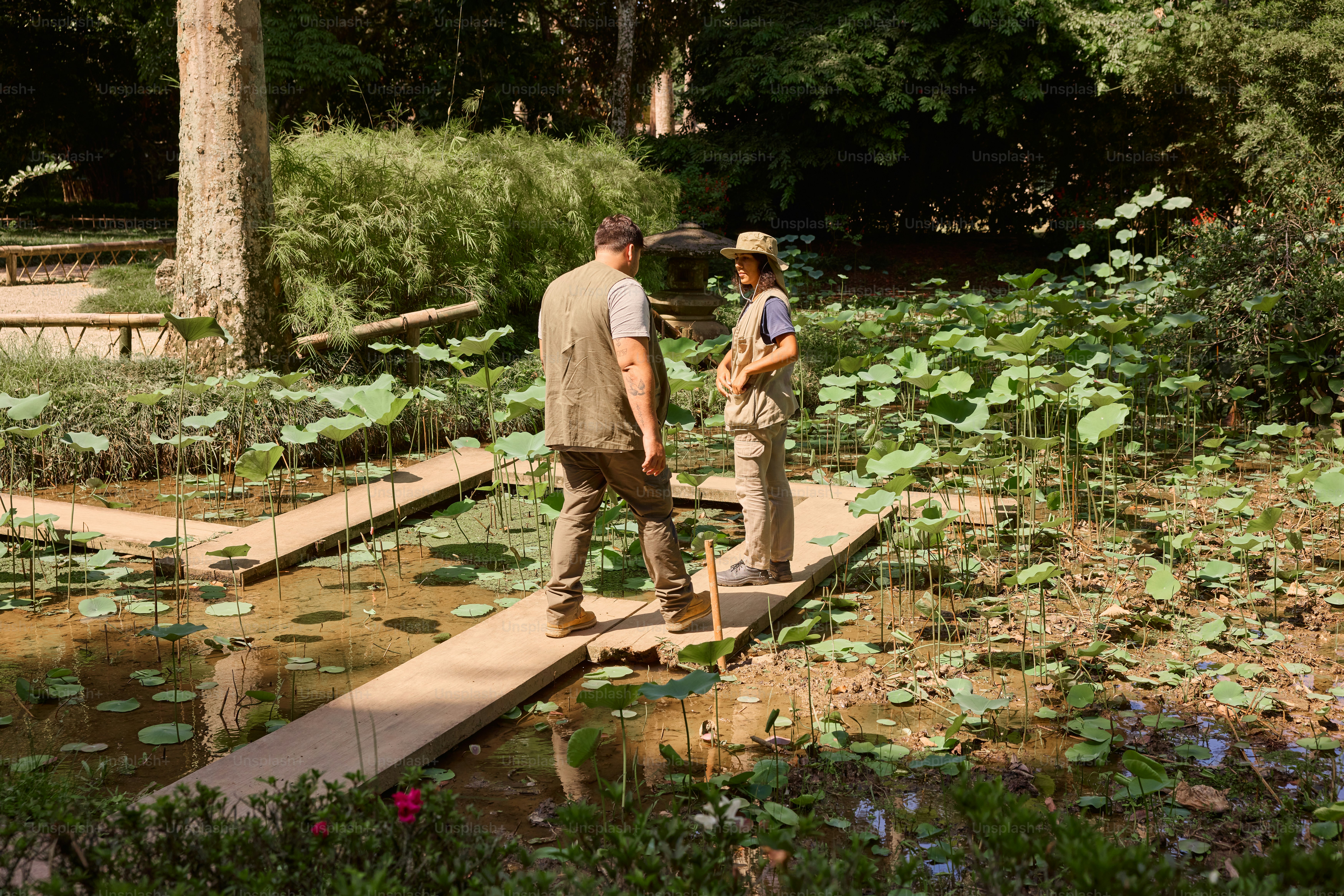 a man and a woman walking across a bridge over a pond