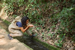 a woman kneeling down next to a small stream