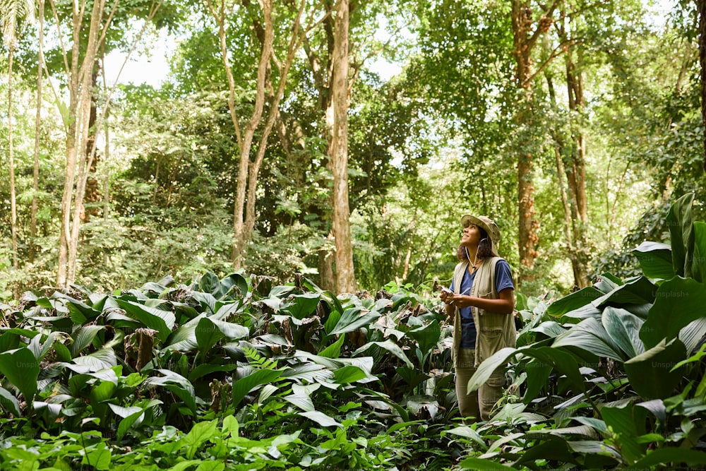 a man standing in the middle of a lush green forest