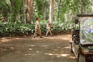 a couple of people walking across a dirt road