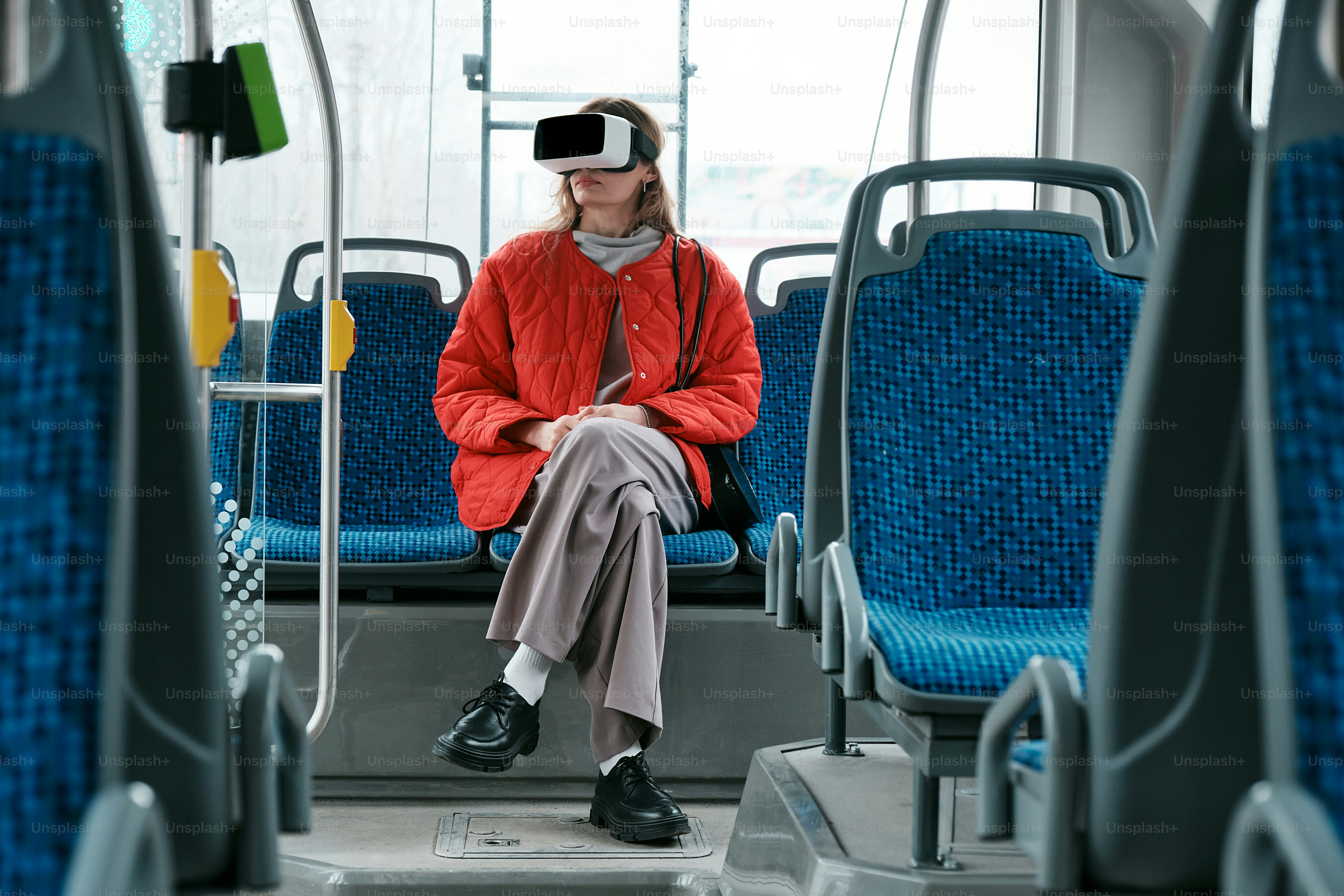 a woman sitting on a bus wearing a virtual headset