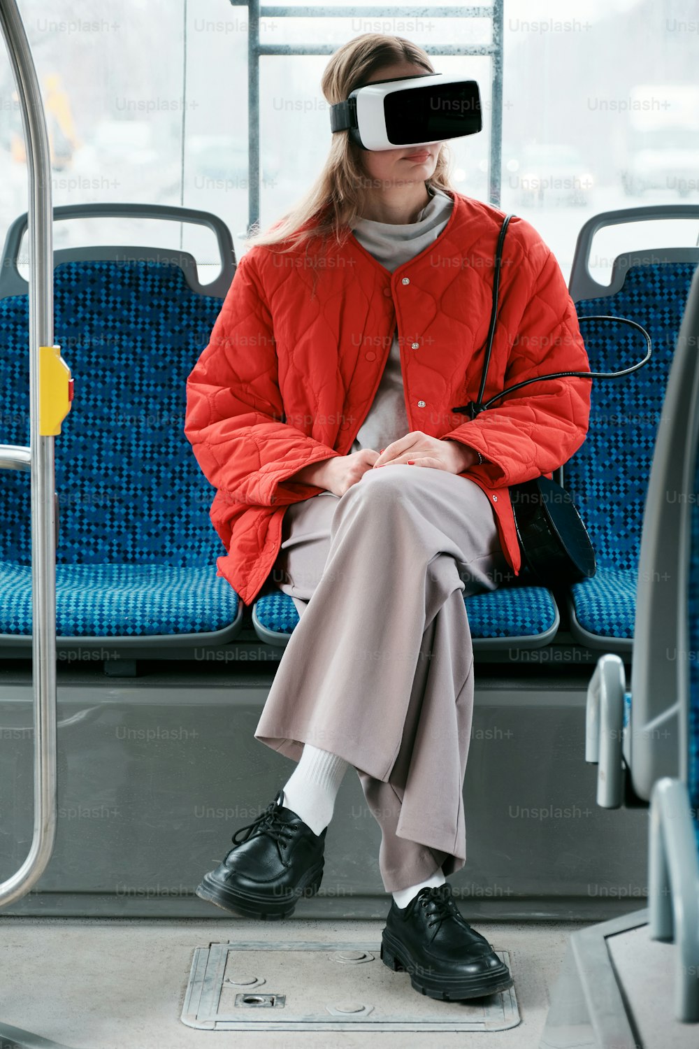 uma mulher sentada em um ônibus vestindo uma jaqueta vermelha