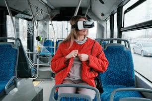 a woman sitting on a bus wearing a virtual reality headset
