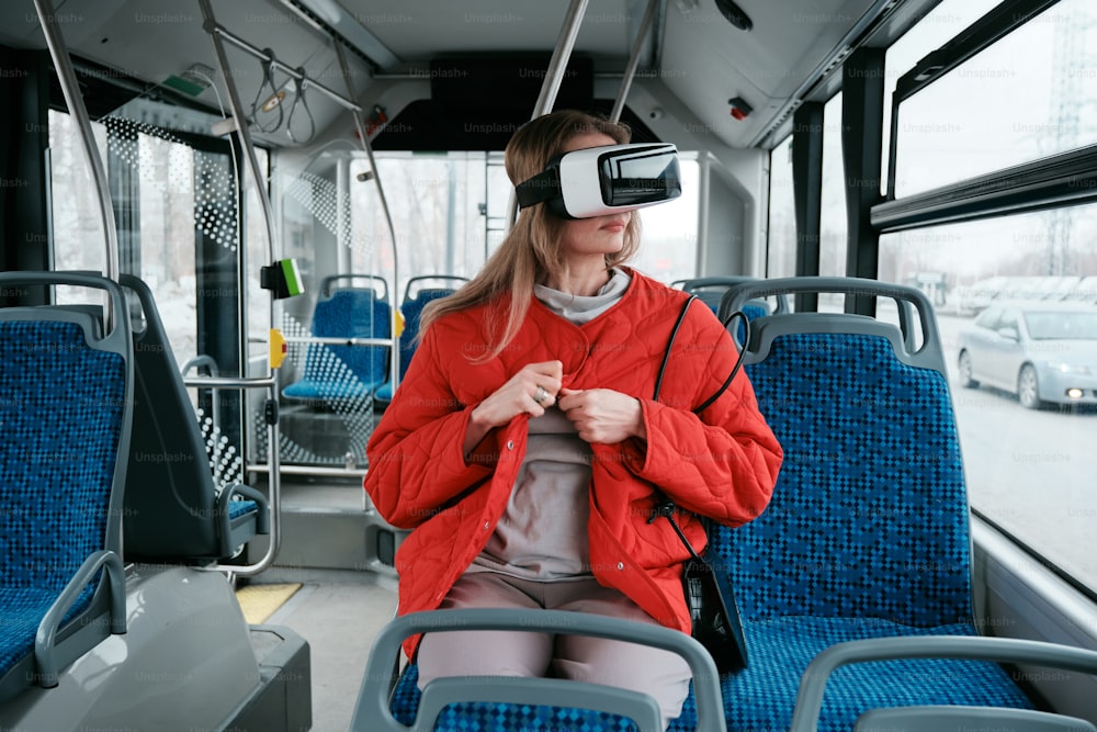 Una mujer sentada en un autobús con un casco de realidad virtual