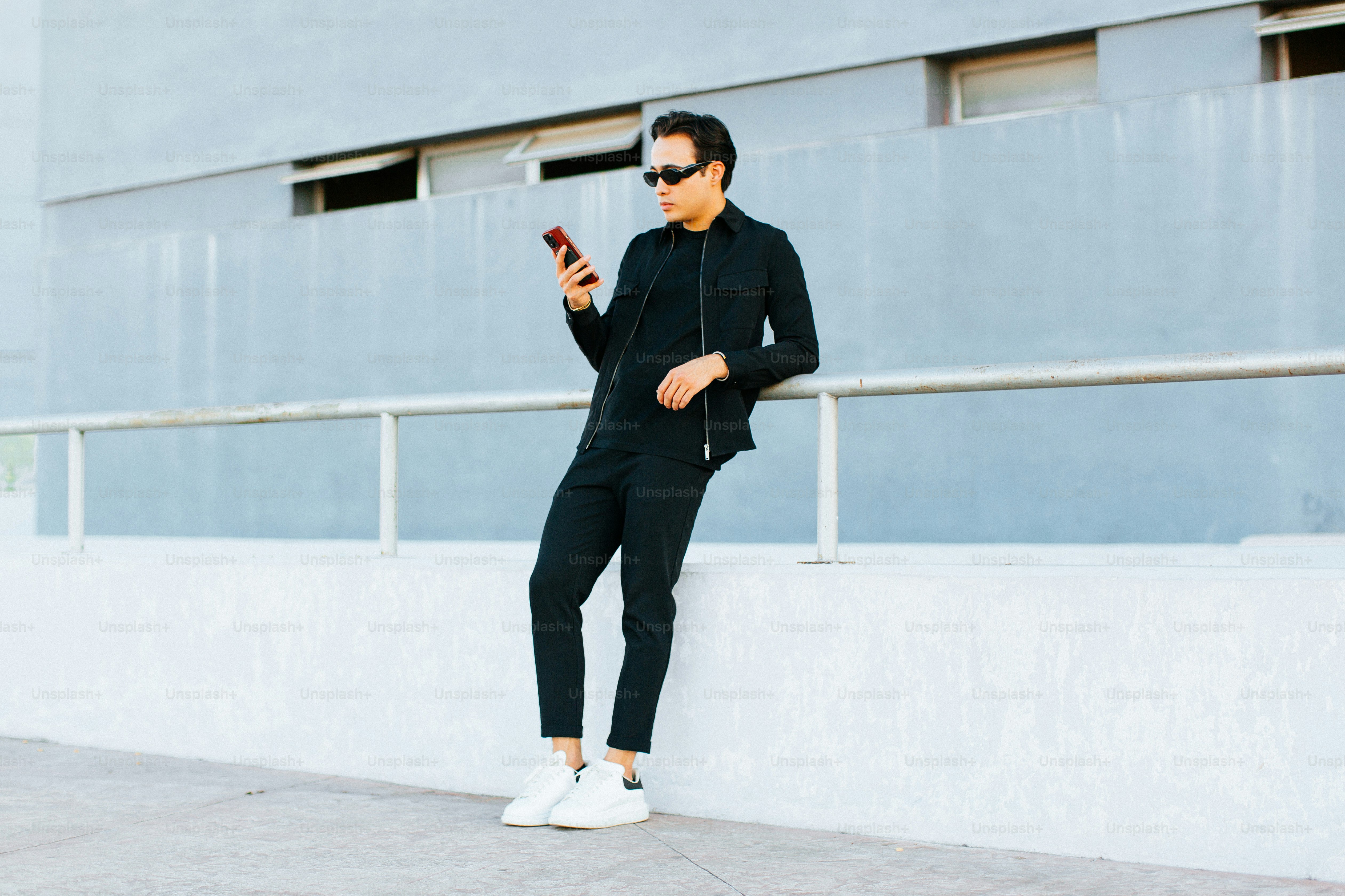 a man leaning against a wall while looking at his cell phone