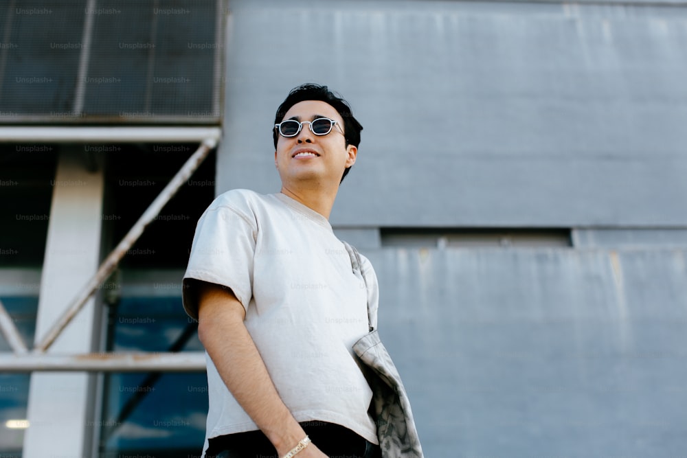 a man wearing sunglasses standing in front of a building