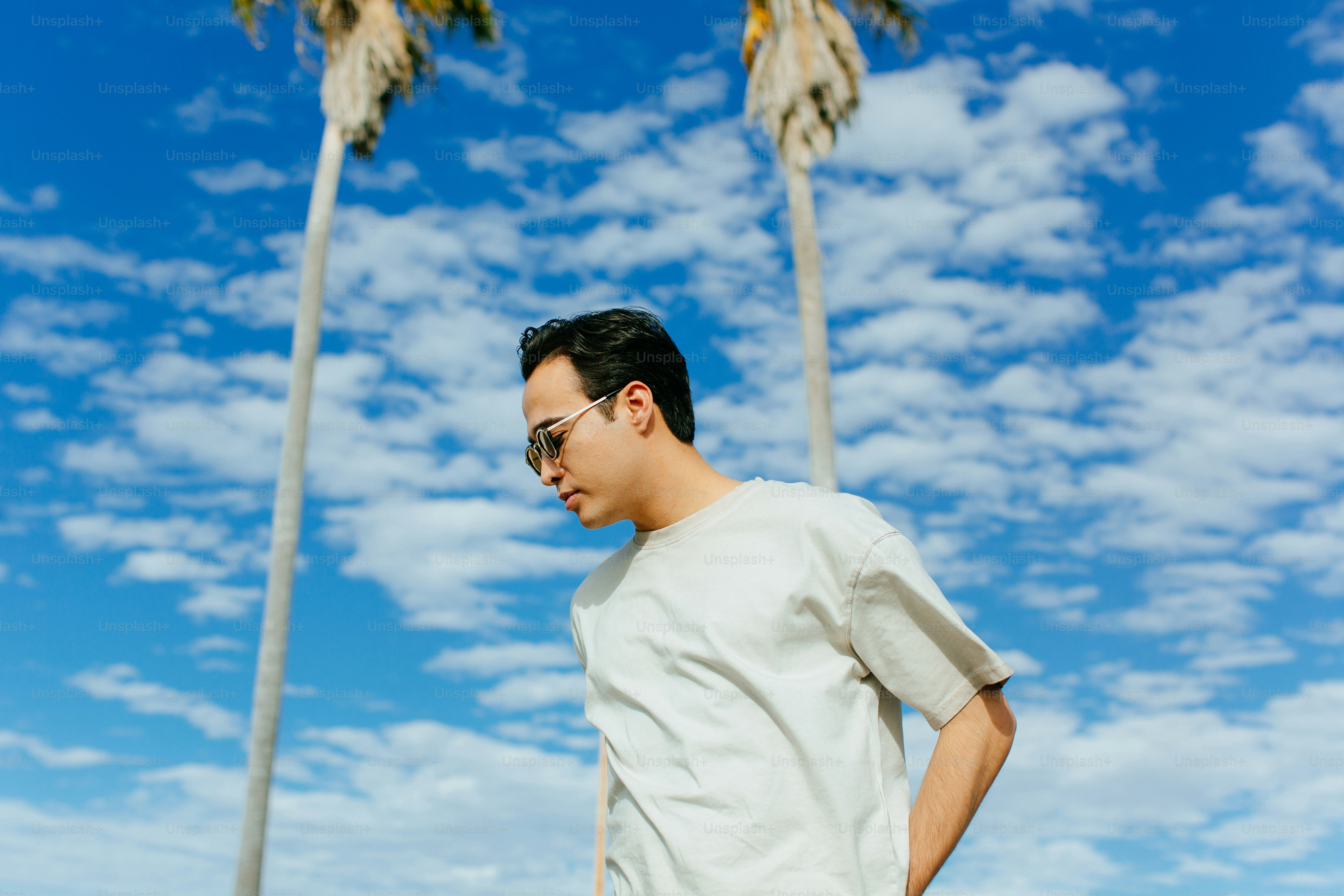 a man standing in front of two palm trees