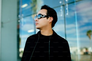 a man wearing sunglasses standing in front of a building