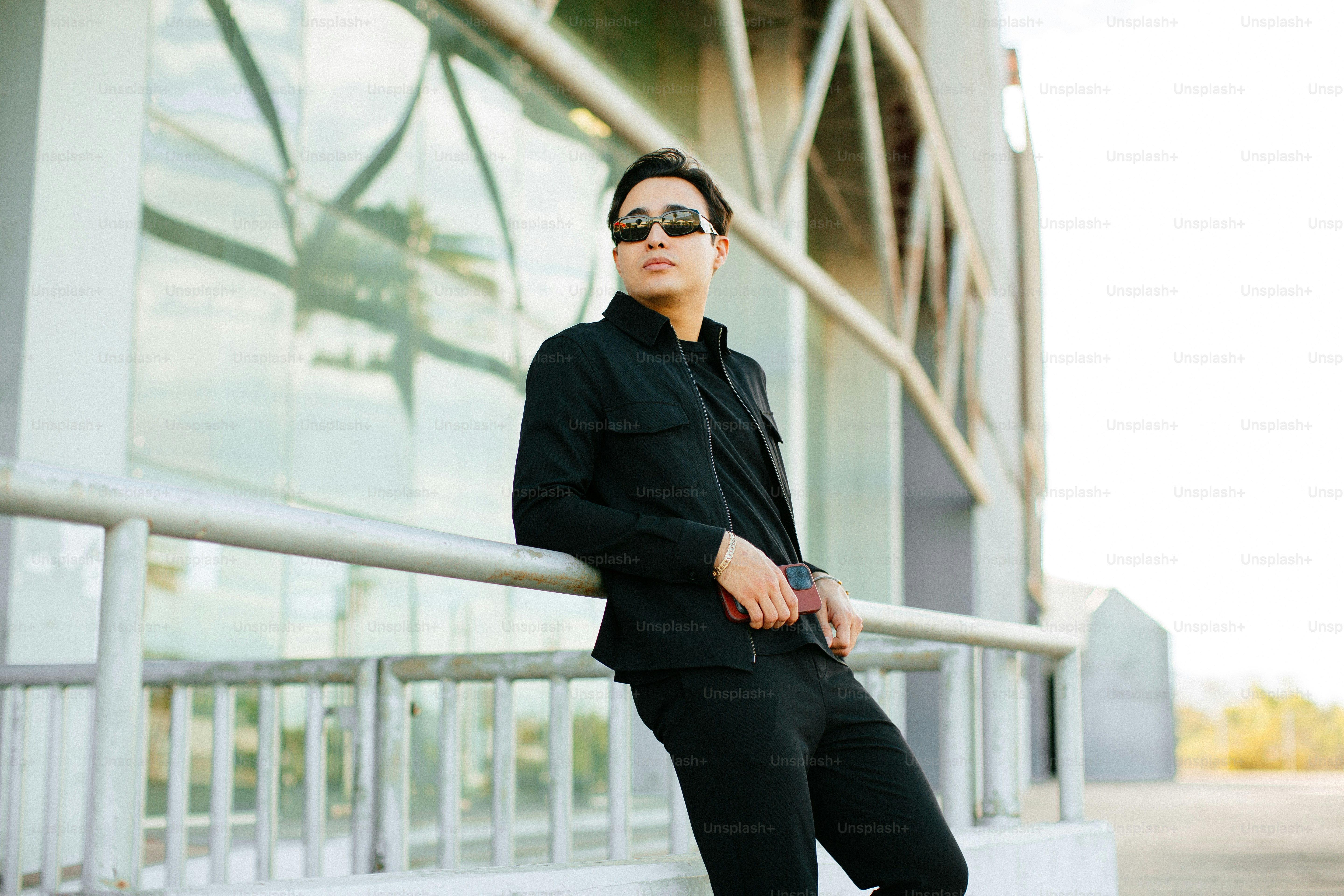 a man in a black suit leaning on a rail