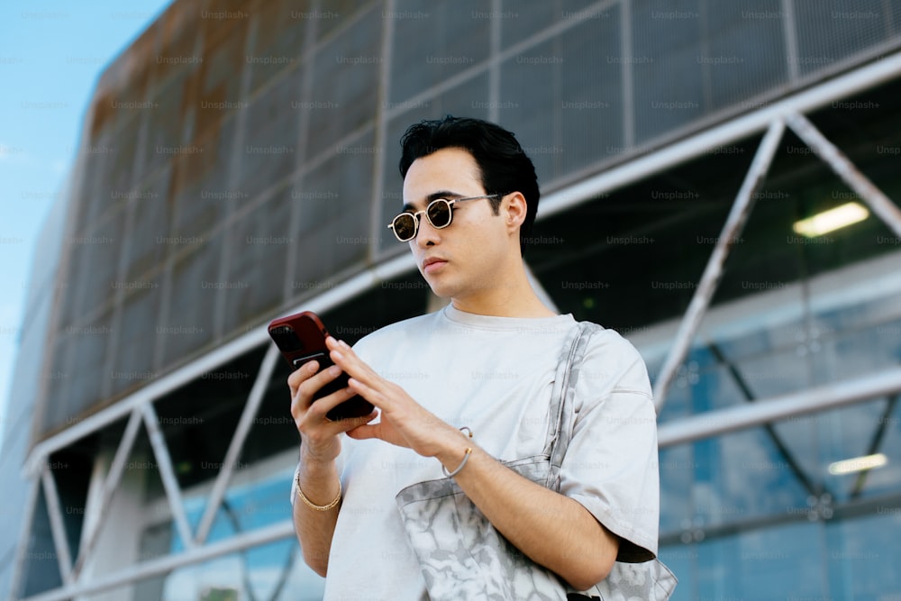 Un hombre con gafas de sol mirando su teléfono móvil