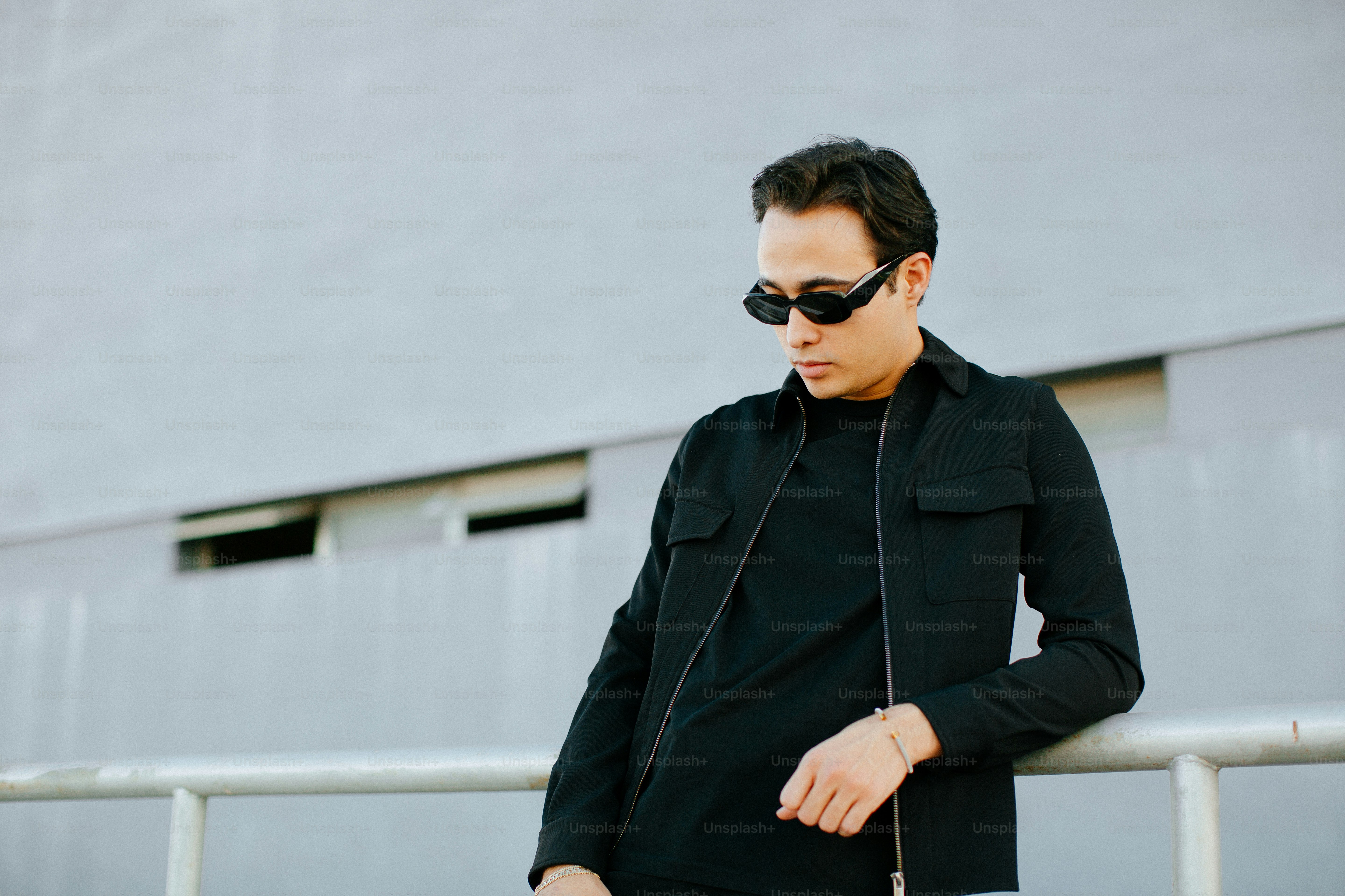 a man wearing sunglasses leaning against a railing