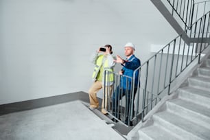 a man taking a picture of another man standing on a stair case