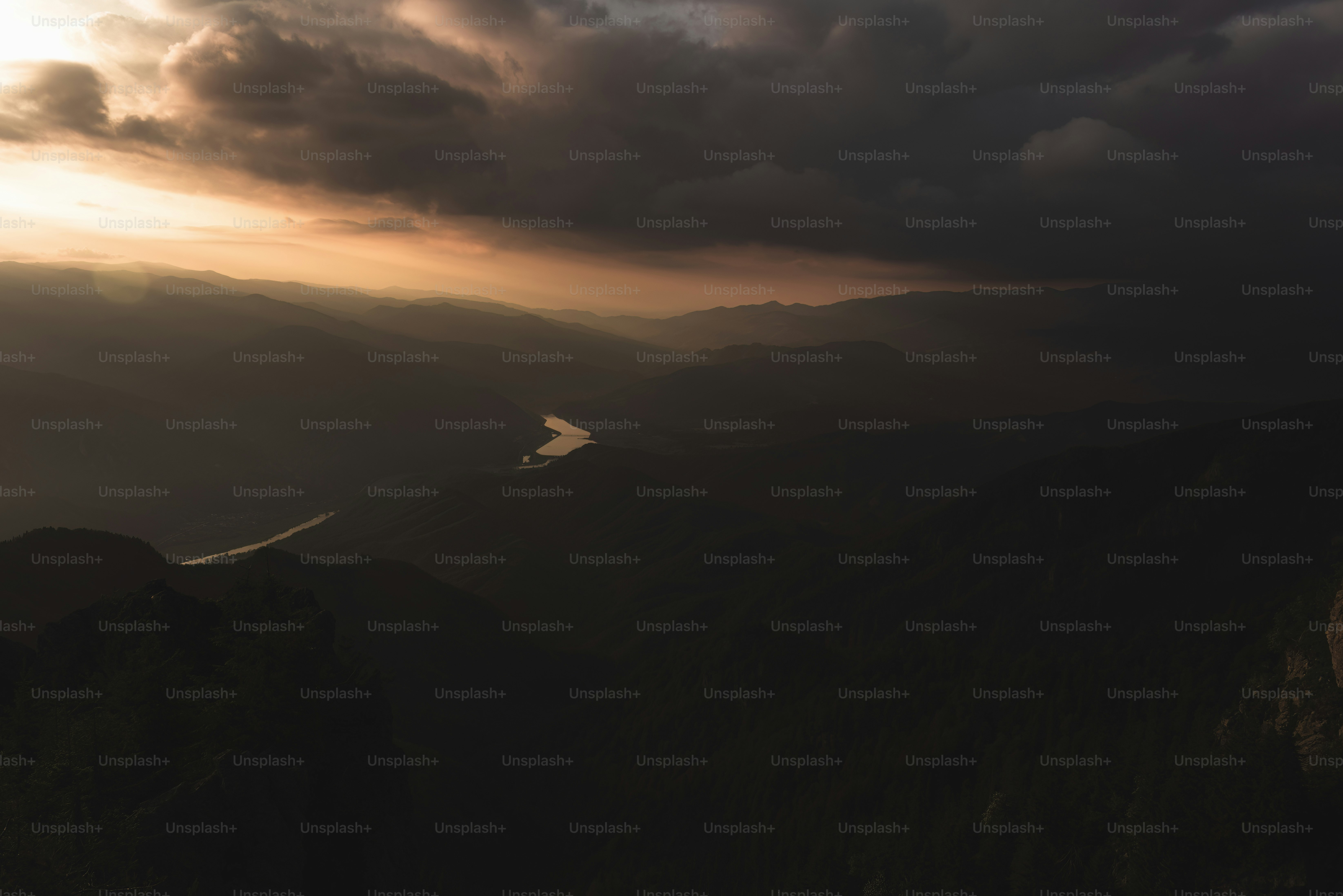 the sun is setting over the mountains and a body of water