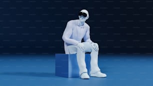 un homme blanc assis au sommet d’un bloc bleu