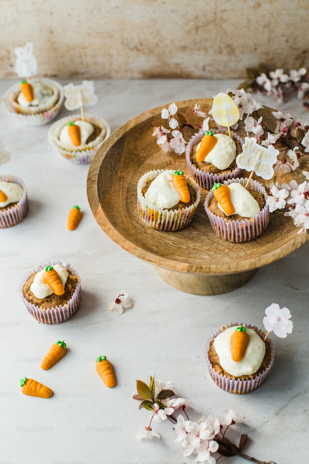 a plate of cupcakes with frosting and carrots