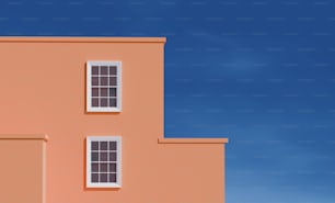 Ein rosafarbenes Gebäude mit drei Fenstern und blauem Himmel im Hintergrund