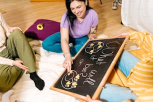 two women sitting on the floor playing with a blackboard