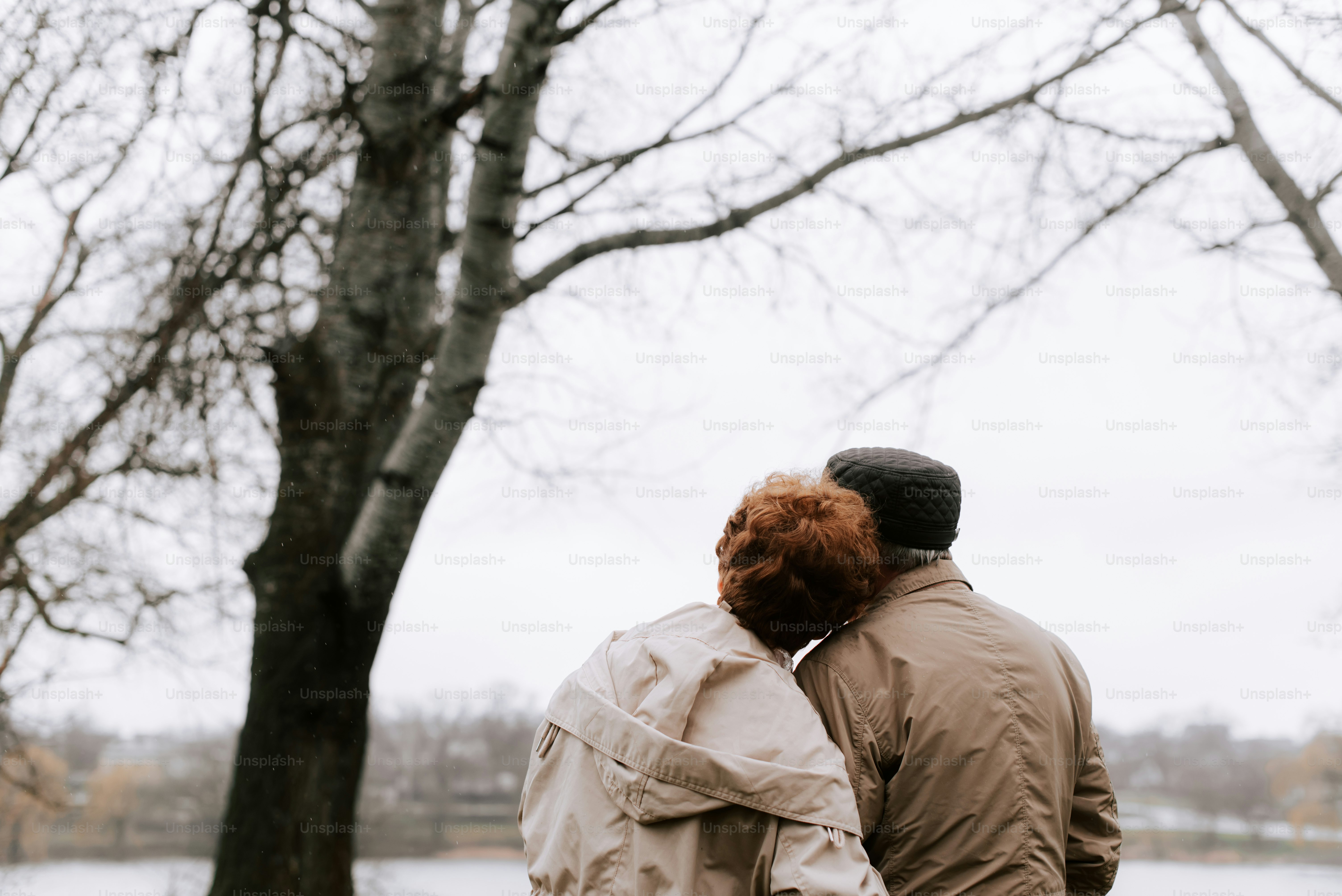 um casal de pessoas em pé ao lado de uma árvore