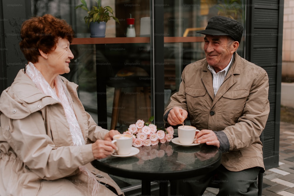 a man and woman sitting at a table with cups of coffee