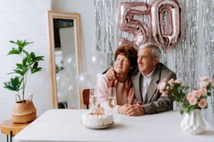 a man and woman sitting at a table with a cake