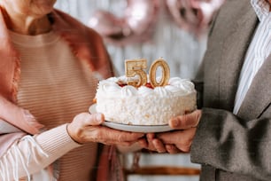 a man and woman holding a cake with the number 50 on it