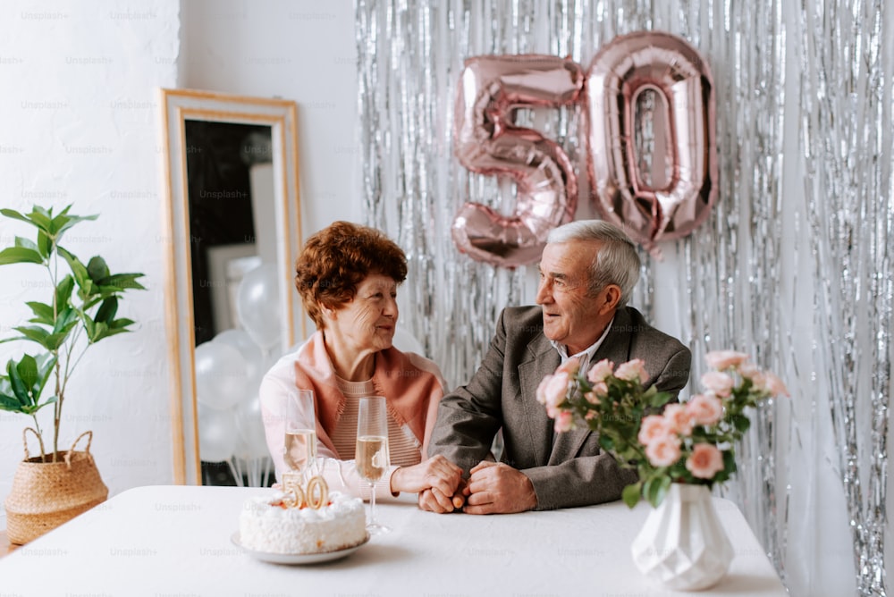 un hombre y una mujer sentados en una mesa con un pastel