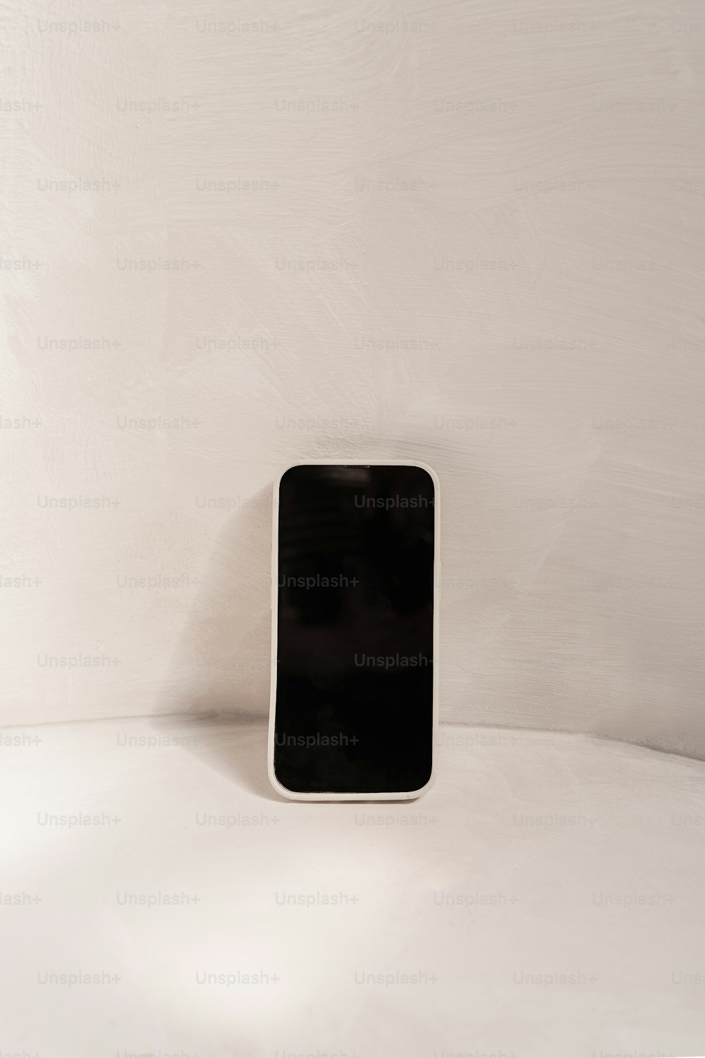 a black cell phone sitting on top of a white table