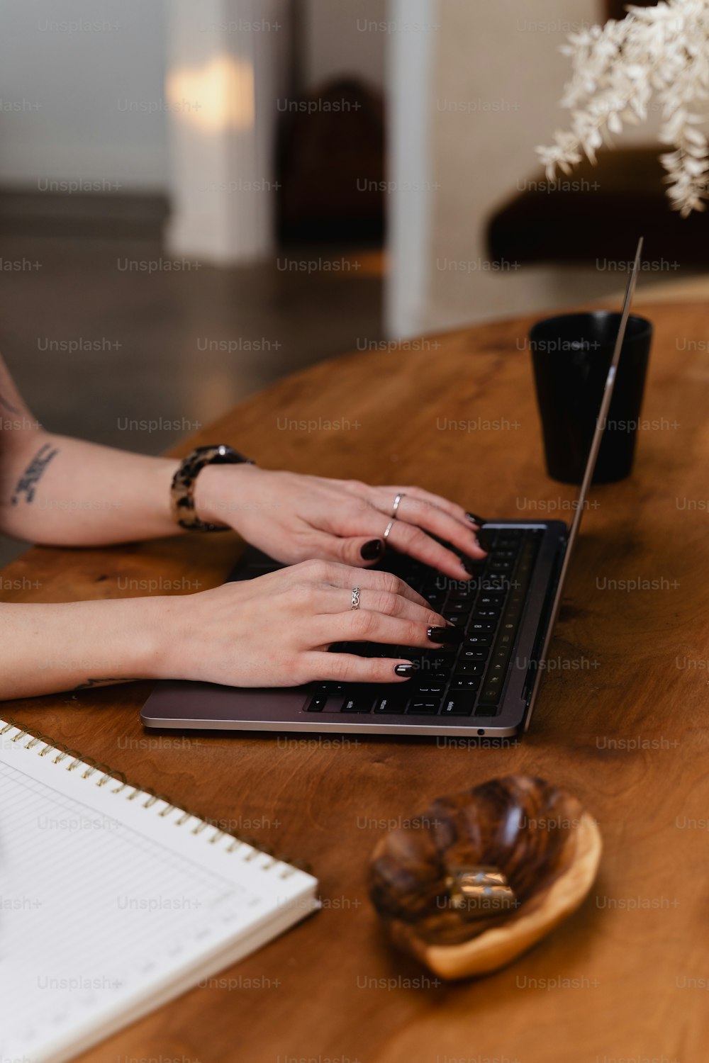 uma mulher digitando em um laptop em uma mesa de madeira