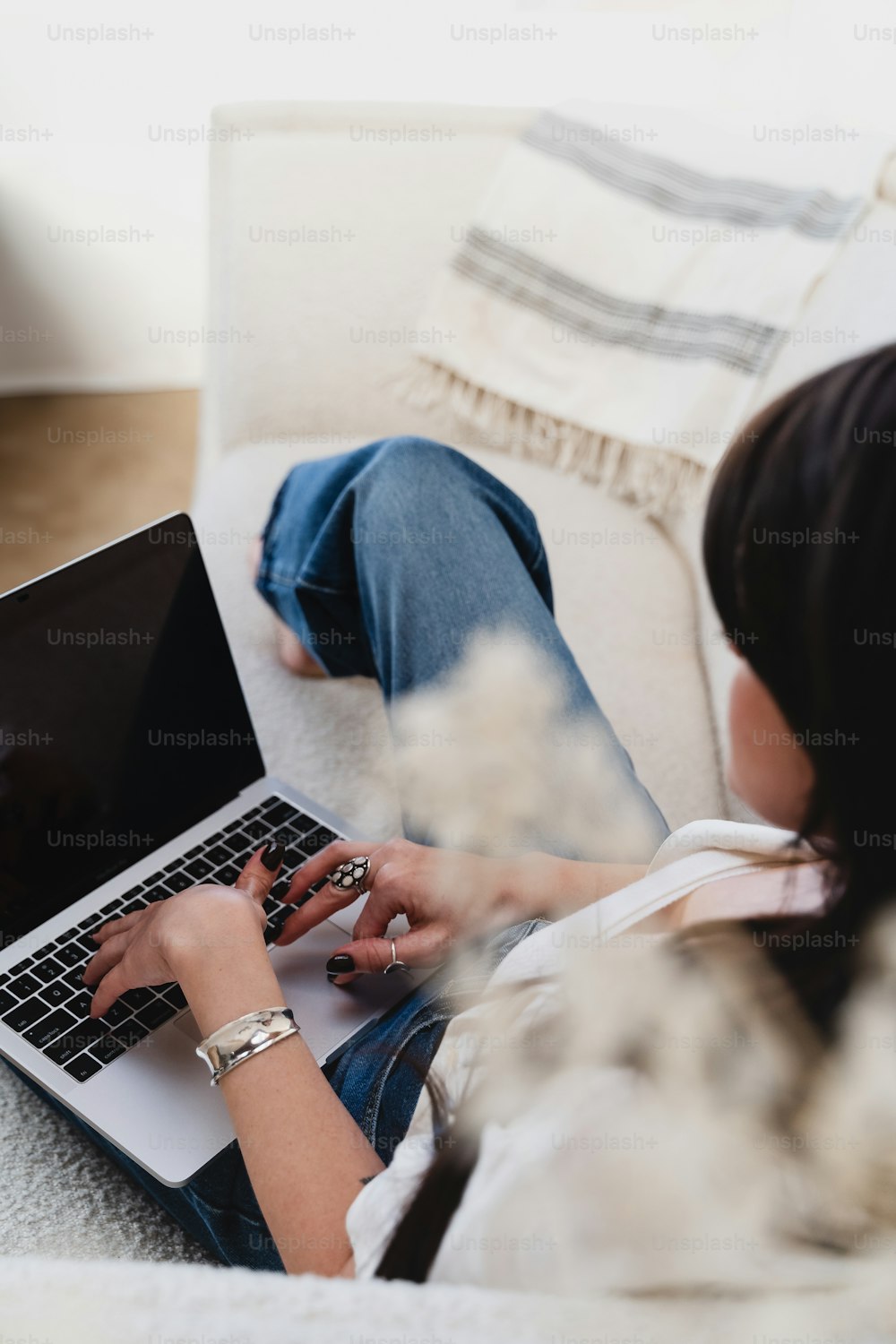 ソファに座ってノー��トパソコンを使う女性