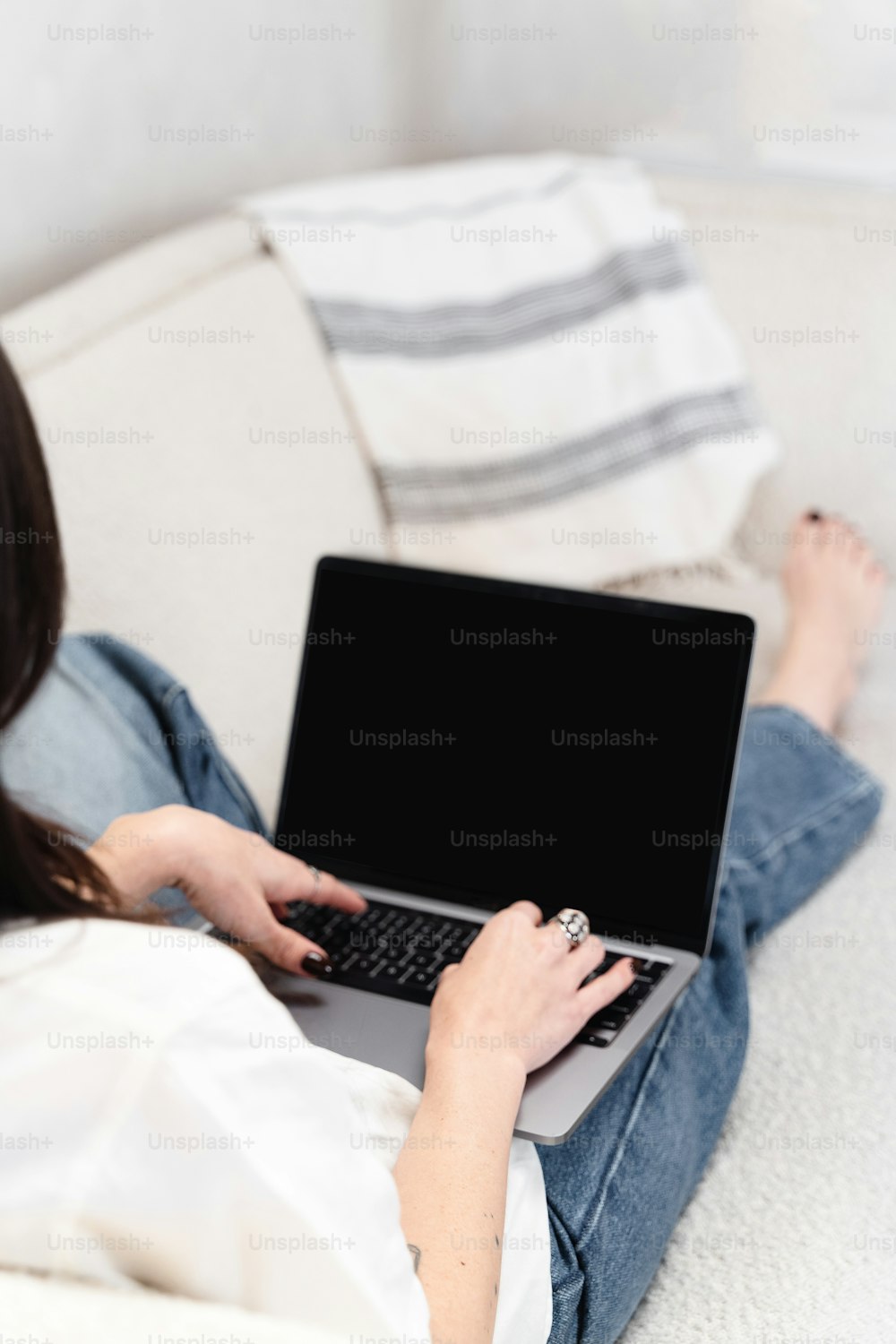 ソファに座ってノートパソコンを使う女性