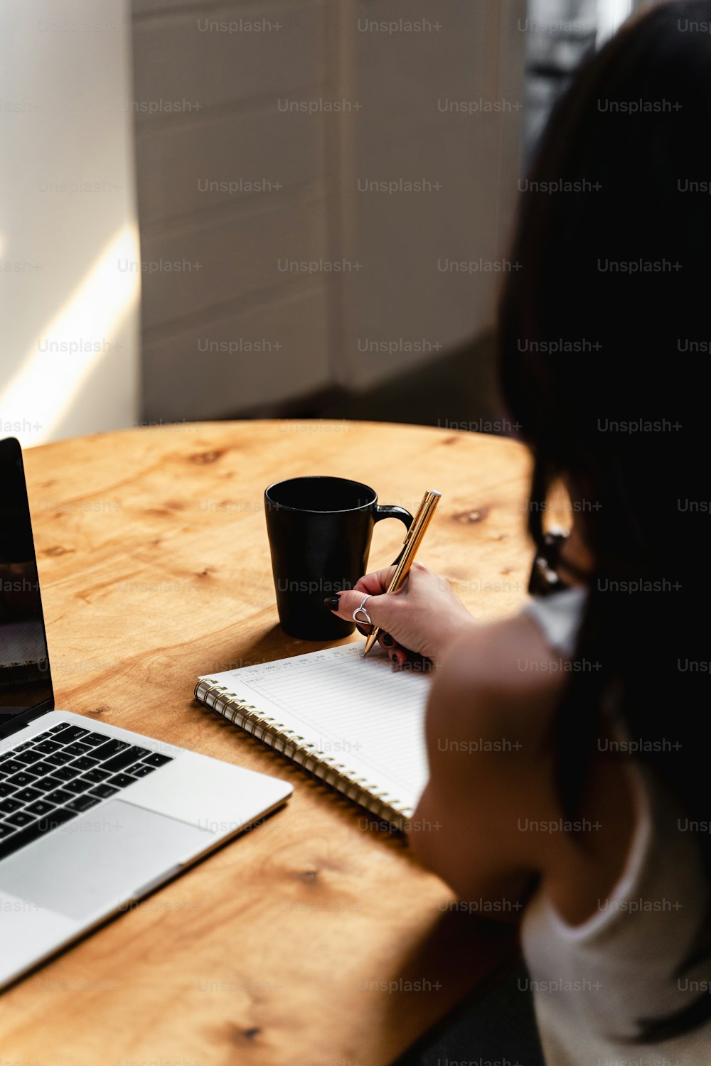 una donna seduta a un tavolo con un computer portatile e una tazza di caffè