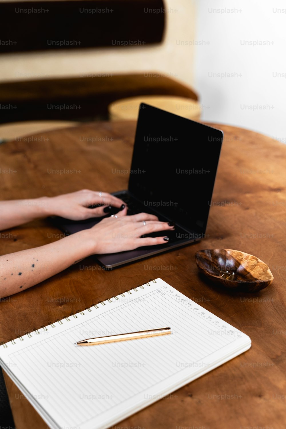 una persona escribiendo en una computadora portátil sobre una mesa de madera
