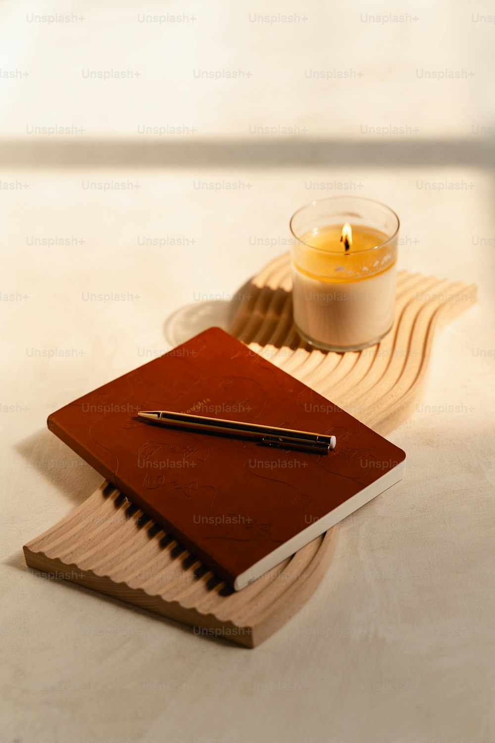 un cuaderno y un bolígrafo en una bandeja con una vela